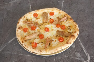 A pizza with meat and tomatoes on top