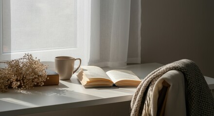 Open book on table by window with mug, dried flowers, and cozy blanket, creating peaceful reading nook