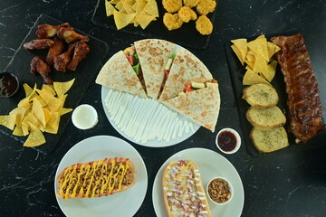 A table with a variety of Mexican food including nachos, tacos