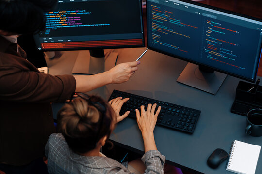 Top view of IT developers discussing with point to intelligent website development coder system running data online two screens information technology at neon light room at modern office. Infobahn.