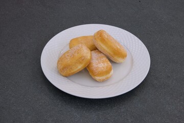 A plate of four donuts with powdered sugar on top