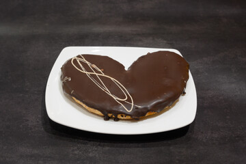 A chocolate heart shaped dessert sits on a white plate