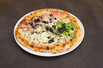 A pizza with a variety of toppings including olives, peppers, and cheese