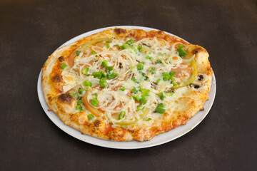 A pizza with vegetables on it is sitting on a white plate