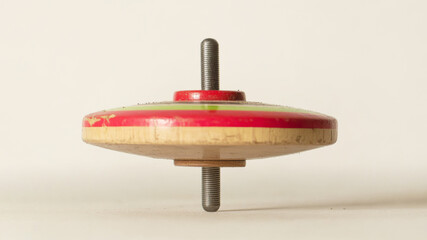 Vintage striped spinning top with a glossy finish, perfectly balanced on its metal axis, evoking childhood memories and traditional games