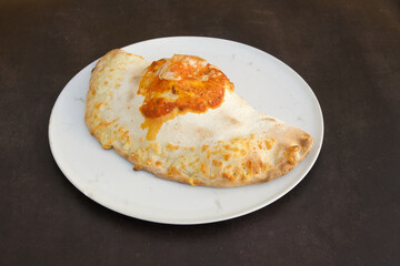 A large pizza with cheese and tomato sauce sits on a white plate
