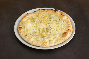 A pizza with cheese and parsley on top of a white plate