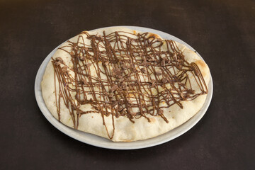A chocolate covered pizza sits on a white plate