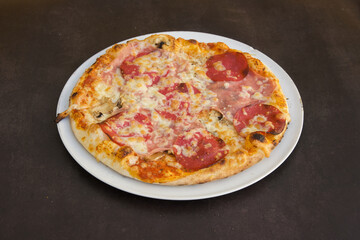 A pizza with pepperoni and cheese sits on a white plate