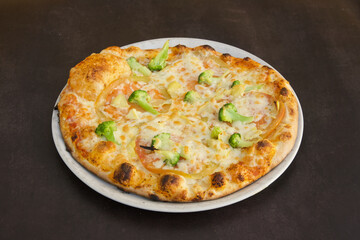 A pizza with broccoli and cheese on a white plate