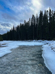 Partially Frozen River Flowing Through Winter Forest