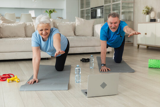 Fitness workout training. Senior adult mature healthy fit couple doing sports exercise on yoga mat on floor at home. Mid age old husband wife have training workout. Health care healthy lifestyle