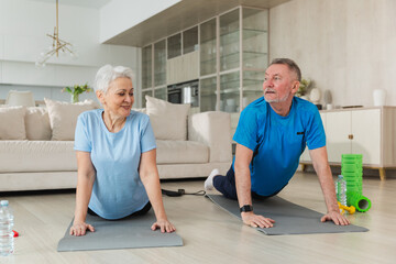 Fitness workout training. Senior adult mature healthy fit couple doing sports exercise on yoga mat on floor at home. Mid age old husband wife have training workout. Health care healthy lifestyle