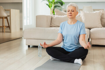 Yoga mindfulness meditation. Senior adult mature woman practicing yoga at home. Mid age old lady...