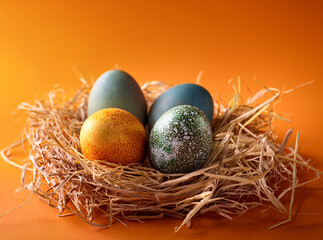 Fototapeta premium easter eggs and colorful easter eggs in nest on blue wooden table. happy easter.