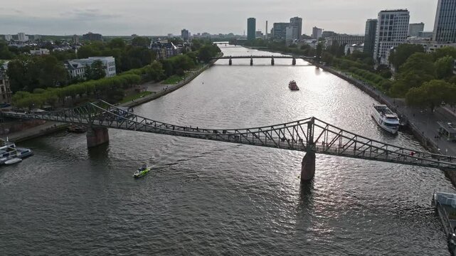 Aerial Drone View of the Iron Footbridge (Eiserner Steg) in Frankfurt, Germany &ndash; Historic Pedestrian Bridge Spanning the Main River, Offering Scenic Views of the City Skyline, Waterfront, and Cultural