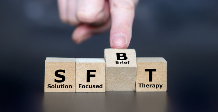 Hand turns cube and changes the acronym SFT (Solution-Focused Therapy) to SFBT (Solution-Focused Brief Therapy). 