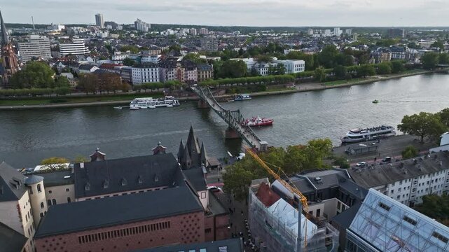 Aerial Drone View of the Iron Footbridge (Eiserner Steg) in Frankfurt, Germany &ndash; Historic Pedestrian Bridge Spanning the Main River, Offering Scenic Views of the City Skyline, Waterfront, and Cultural