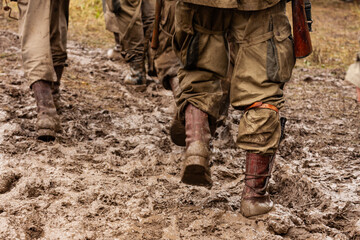World War II historical reenactment.  Close-up. Dirty, muddy uniforms and boots of US paratroopers...