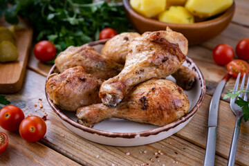 Hearty dinner: delicious grilled chicken legs on a plate. Grilled chicken legs for a family dinner on a plate on a wooden table. Close-up