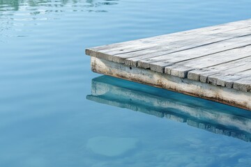 Naklejka premium A weathered wooden dock extends over calm, turquoise water, reflecting serenity.
