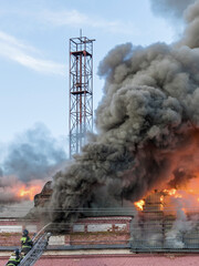 Fototapeta premium Fire is burning and a firefighter is spraying water on it