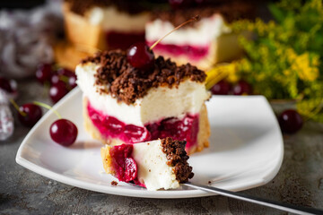 A piece of cherry pie with cream on a white plate for dessert. Close-up