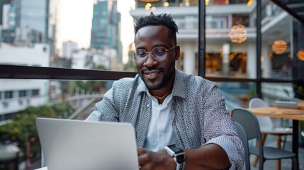 Naklejka premium Freelancer works on laptop in remote cafe with urban backdrop during relaxed afternoon