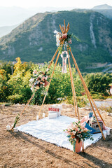 Wedding arch-wigwam with a blanket, candles and flowers stands on the mountain