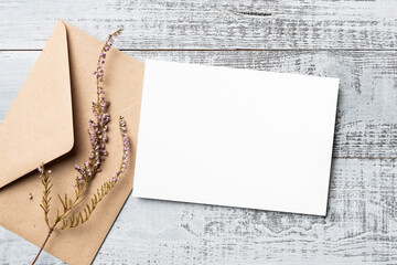 Blank invitation card mockup with craft envelope and dried flowers decor, copy space for card...