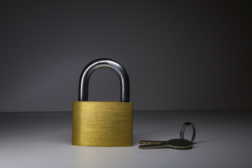 Gold-colored lock and keys, on a gray background, close-up