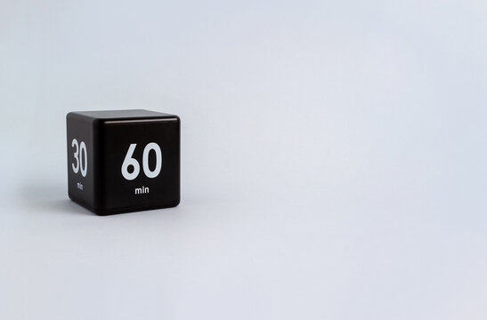 Black cube timer with 60 and 30 minutes sign on grey background. Minimal interval time concept. Copy space, selective focus