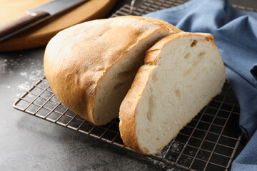 Cut fresh bread and knife on grey table, closeup