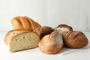 Whole and cut bread loafs on white table