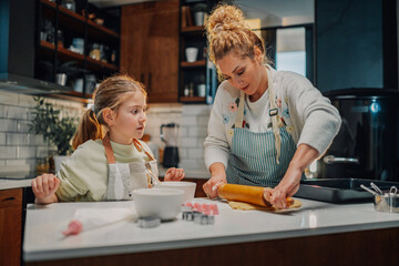 Fototapeta premium Mother and daughter making cookies in modern kitchen