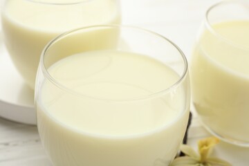 Delicious vanilla milk in glasses on white table, closeup