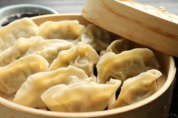 Tasty boiled gyoza (dumplings) in bamboo steamer on table, closeup