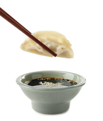 Dipping tasty gyoza (dumpling) into soy sauce on white background