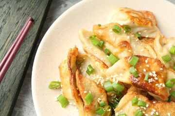 Tasty fried gyoza (dumplings) and chopsticks on light grey table, top view