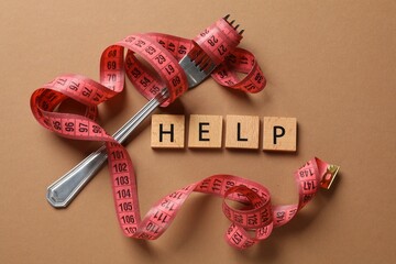 Bulimia. Word Help, fork and measuring tape on brown background, top view
