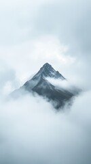 Obraz premium Majestic Mountain Peak Surrounded by Misty Clouds and Soft Light