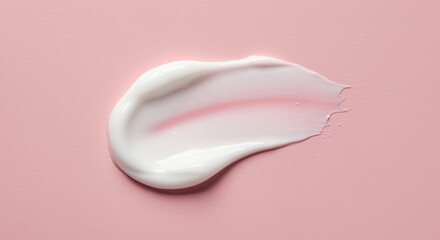 Close-up of smooth white skincare cream texture on a pastel pink background.