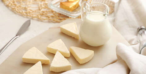 Board with triangles of tasty processed cheese and milk on light background, closeup