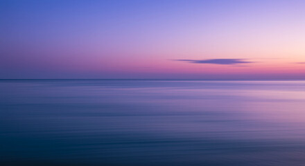 Obraz premium Serene ocean horizon at sunset with soft gradient colors in the sky and water.