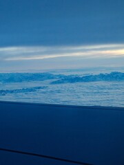 A plane wing soaring over snowy peaks
