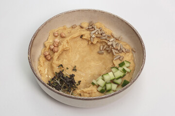 The image shows a bowl filled with a creamy, pale yellow hummus. 
