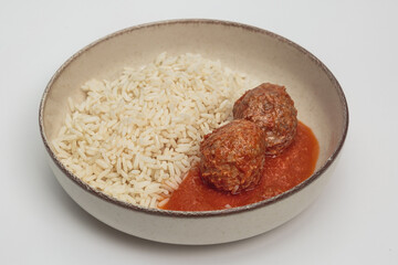 The image shows a simple, yet appetizing dish consisting of plain white rice and two meatballs in a tomato sauce.
