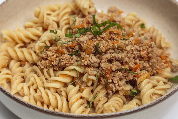 This image shows a bowl of pasta with a hearty meat sauce