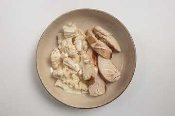 The image shows a bowl filled with a variety of cooked and sliced chicken pieces, as well as pieces of fresh cauliflower. 