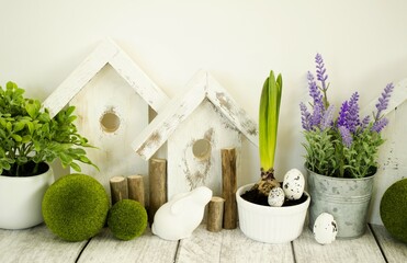Easter decorative composition, home decoration for the holiday of bright Easter. On the table are cute rabbits and wooden houses, front view.